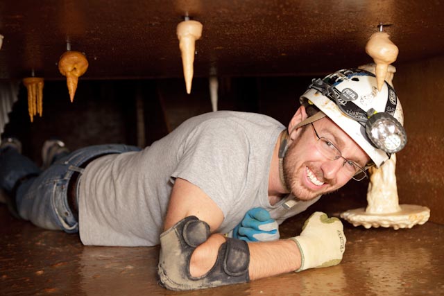 A smiling man in a helmet explores an artificial cave tunnel