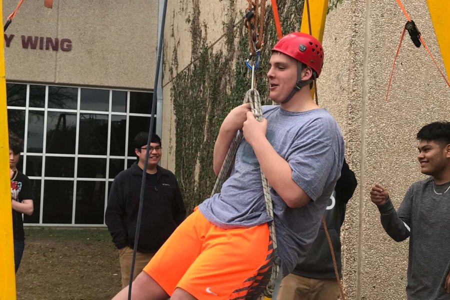 Austin, TX: A student gets lifted by classmates up the CaveSim tower using pulley systems